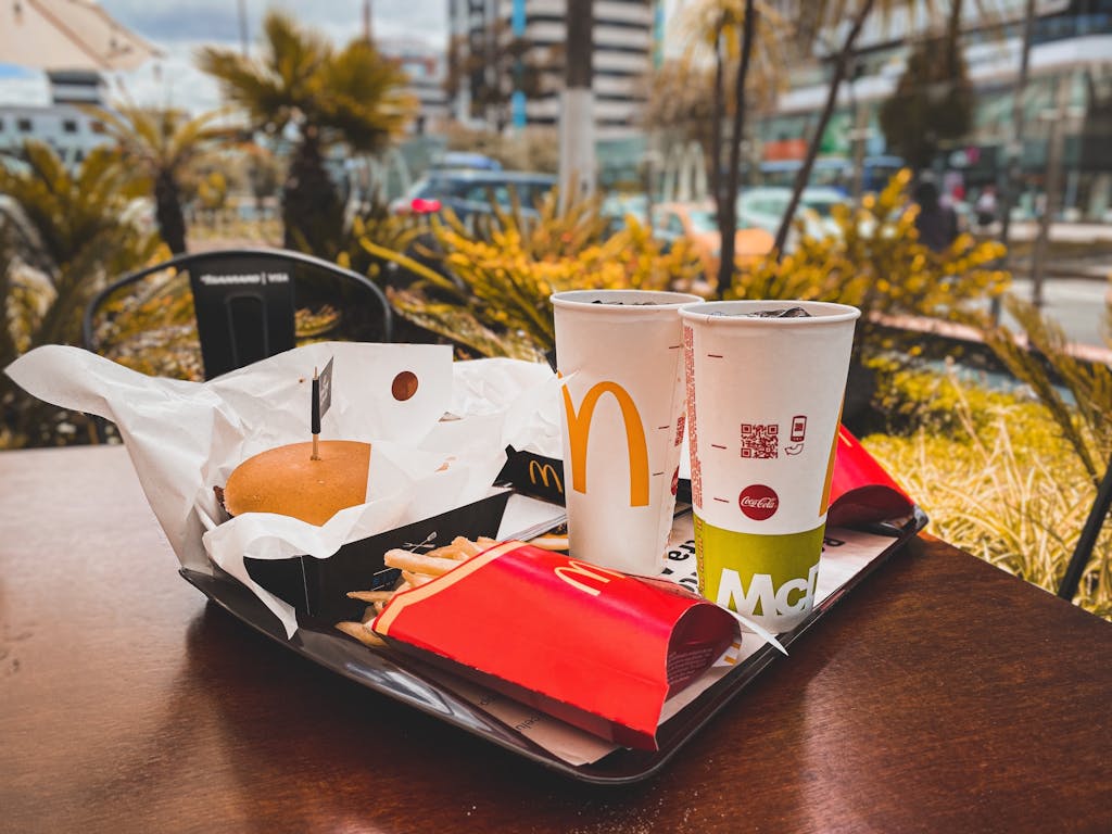 Pasto fast food con hamburger, patatine e bevande su un tavolo all'aperto in citta