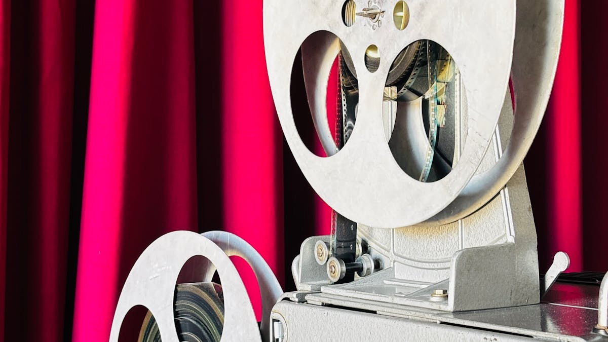 Proiettore cinematografico antico davanti a un sipario rosso, simbolo del cinema russo classico