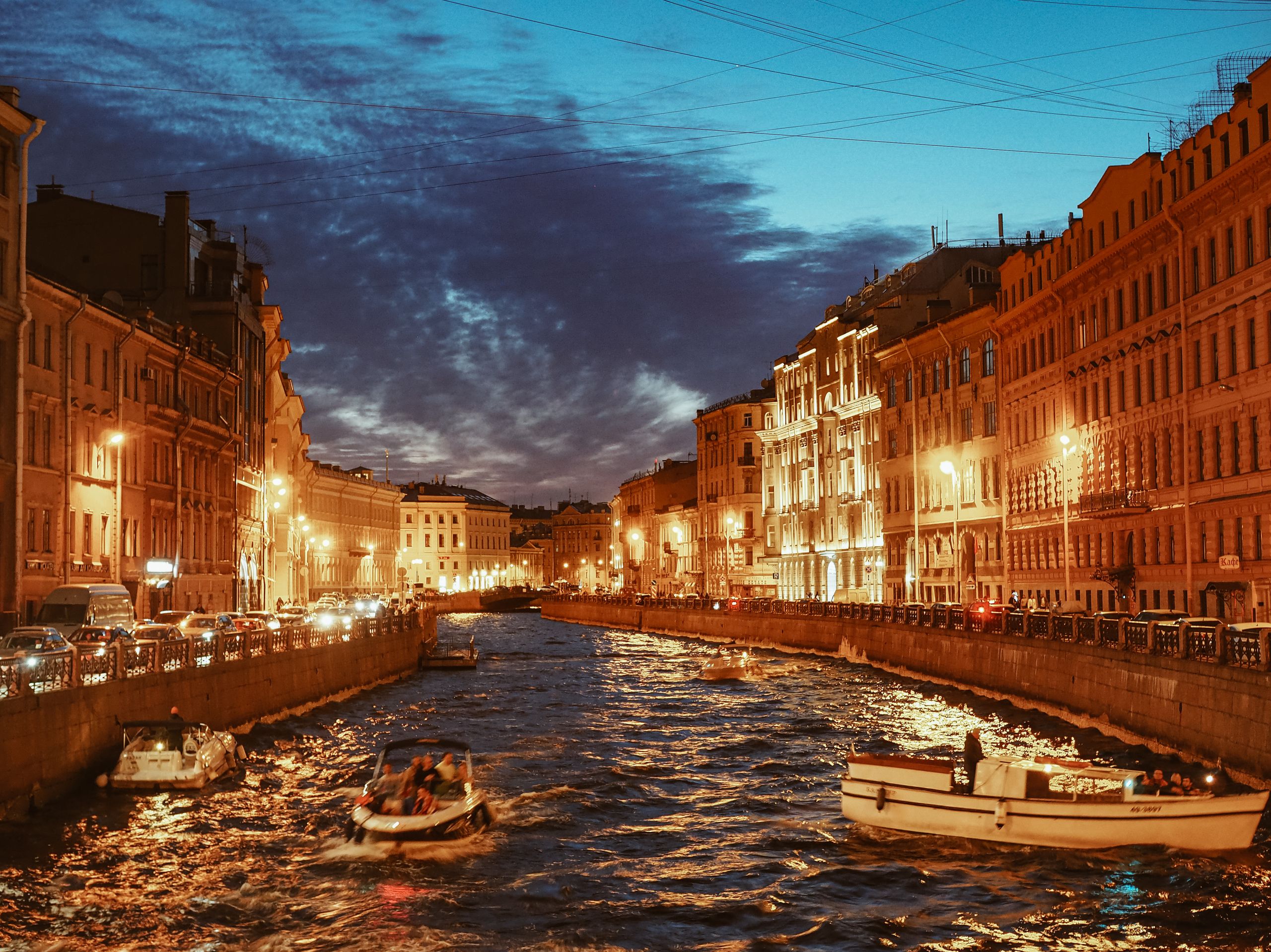 Vista al tramonto di un canale di San Pietroburgo con edifici illuminati e barche